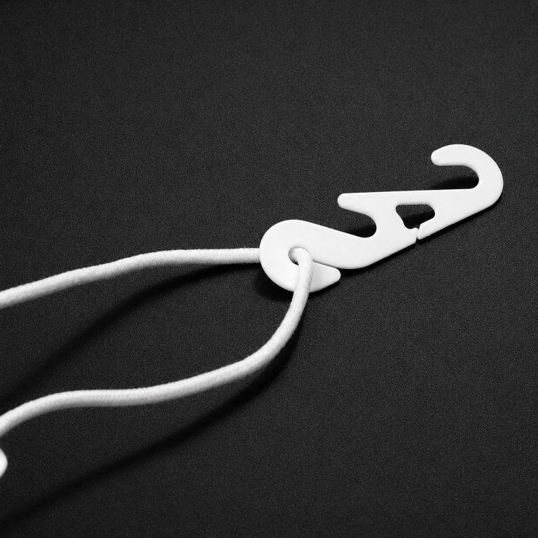 White plastic mask earloop extender hook applied on a folding mask for comfortable fit
