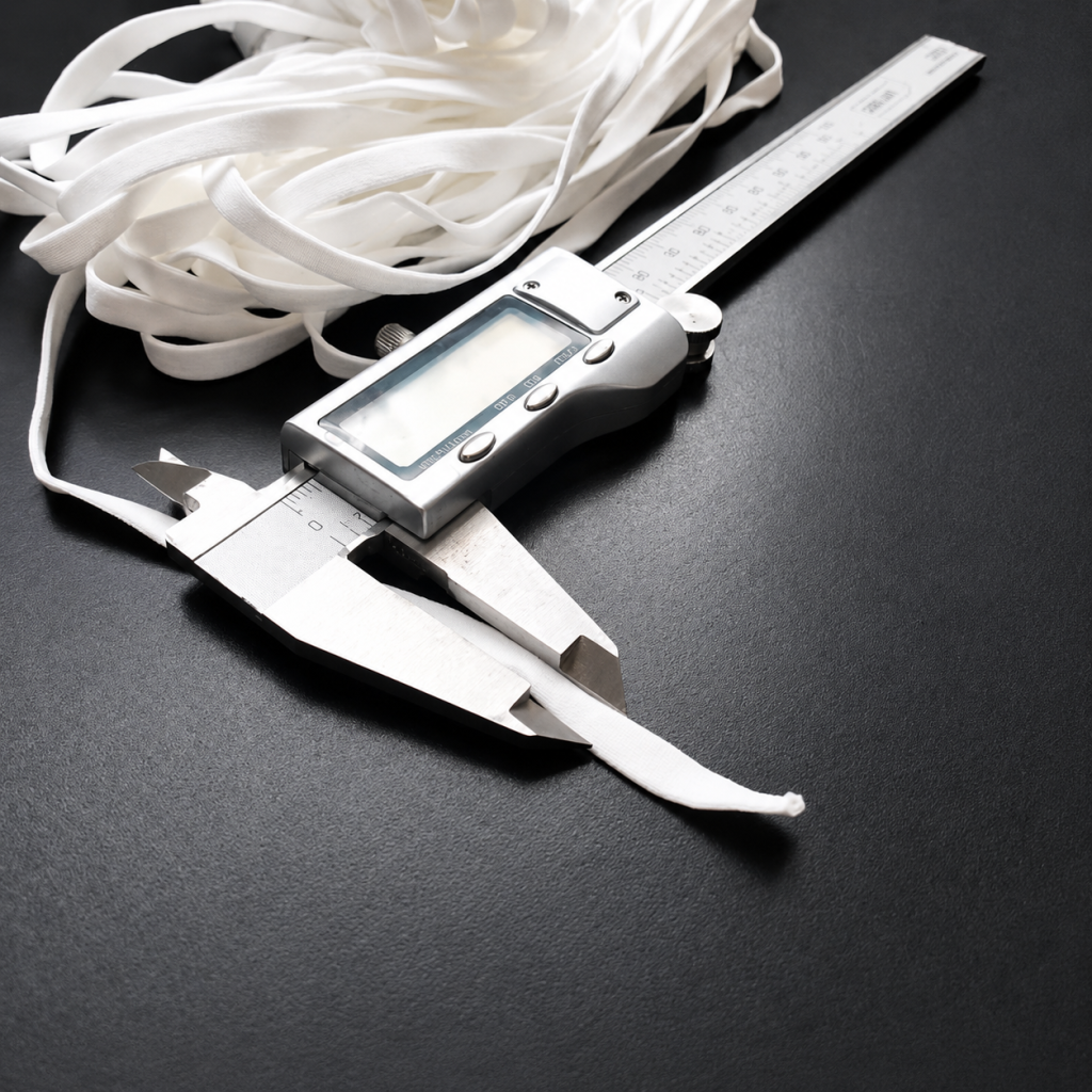 Measuring the width of a white hollow flat earloop with a digital caliper - Zhaowen Quality