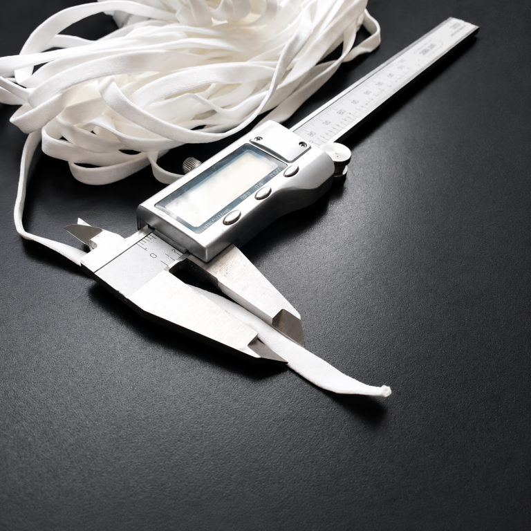 Measuring the width of a white hollow flat earloop with a digital caliper - Zhaowen Quality