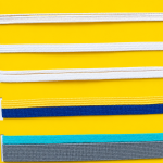 Wholesale rolls of white flat braided elastic mask band on dark background